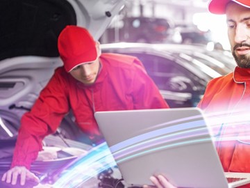 Glasfaserverbindung in Werkstatt & Autohaus enviaTEL KFZ-Mechatroniker arbeitet mit Laptop und envia-TEL-Glasfaserverbindung