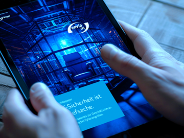 Whitepaper Cyber-Sicherheit ist Chefsache Mann hält ein Tablet in der Hand, das Tablet zeigt das Cover des Whitepapers Cyber-Sicherheit ist Chefsache mit dem envia TEL Logo