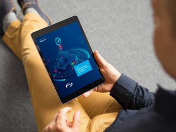 Whitepaper ebook Firewall Selbst oder Service Ein Mann sitzt auf dem Boden, hält ein E-Book in der Hand und liest den Bericht zur Cybersicherheit der envia TEL