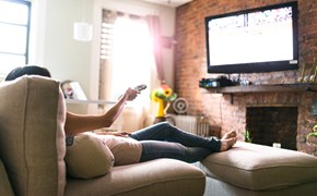 IPTV für Wiederverkäufer Frau sitzt auf dem Sessel und schaut Fernsehen