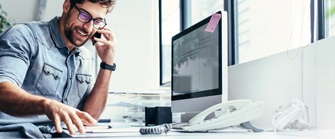 VoIP für Unternehmen Mann sitzt am Schreibtisch und telefoniert