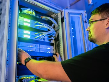 Werkstudentenjob bei der envia TEL Auszubildender bei der Arbeit vor einem Serverschrank